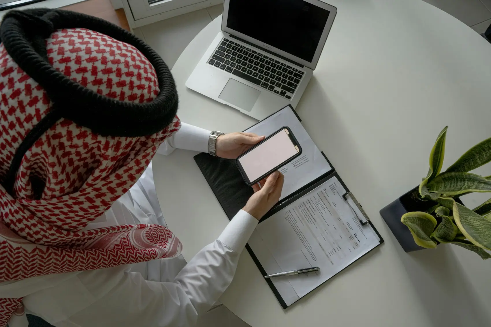 رجل أعمال سعودي يراجع جواله على مكتبه
